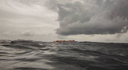 Migrantes a bordo de un bote que partió de Libia aguardan su rescate en el Mediterráneo Central.