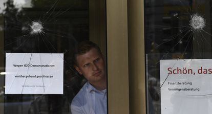 Un empleado del banco Haspa Sparkasse coloca el cartel "Debido a la manifestación del G20 cerramos temporalmente" en el acceso a la entidad, en Hamburgo.