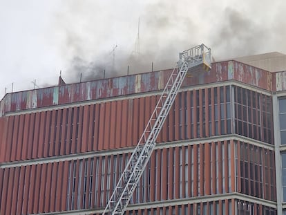 Los bomberos intentan sacar empleados del edificio durante el incendio.