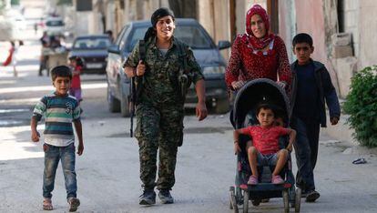 Una miliciana kurda, junto a una familia, en Kobane.