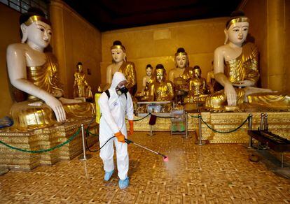 Un voluntario rocía desinfectante entre las estatuas e iconos de Buda para frenar la propagación del Covid-19 en la pagoda sagrada de Shwedagon en Yangon (Myanmar). El país suma hasta ahora 14 casos.