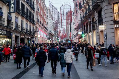 Cientos de personas, con compras, en la calle comercial de Preciados, en Madrid.