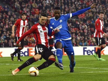El defensa camerunés del Olympique de Marsella, Nicolas Nkoulou pelea un balón con el delantero del Athletic Club de Bilbao Aritz Aduriz en el partido de vuelta de octavos de final de la Europa League celebrado en San Mamés.