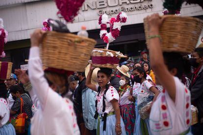 Un grupo de mujeres carga canastas con arreglos florales durante la marcha obradorista.