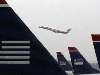 Un avi&oacute;n de American Airlines despega entre aviones de US Airways estacionados en el aeropuerto Ronald Reagan de Washington.