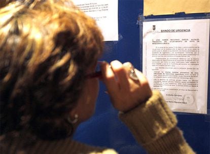 Una mujer lee el bando del Ayuntamiento de Hoyo de Manzanares en el que se dan instruciones en caso de contagio.