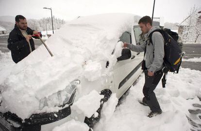 Dos peregrinos de Barcelona que realizan el Camino de Santiago retiran la nieve acumulada en un vehículo en Roncesvalles (Navarra).