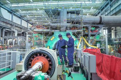 Dos ingenieros inspeccionan la maquinaria del generador en una central nuclear durante una interrupción.