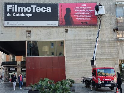 Una grúa cuelga el cartel de los 10 años de la Filmoteca en el Raval.