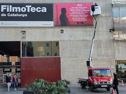 Una grúa cuelga el cartel de los 10 años de la Filmoteca en el Raval.