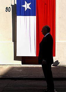 Lagos, frente a la puerta de La Moneda, cubierta con una bandera chilena.