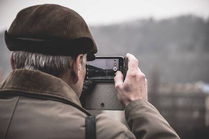 Una persona mayor de 60 años toma una foto con un móvil.
