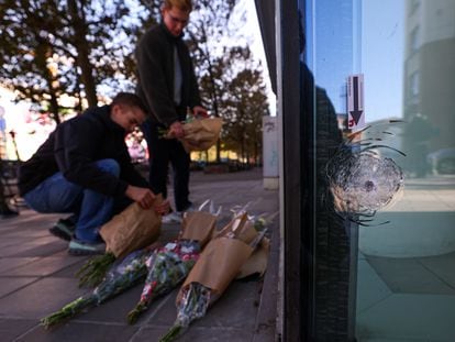 Personas depositan flores en la sede bancaria de Bruselas donde dos hinchas suecos fueron abatidos el lunes por un terrorista